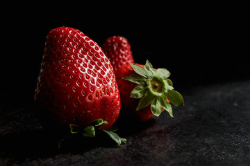 Strawberries on black textured background, dark food