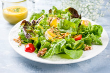 Traditional Germen Summer Lettuce With Curled Lettuce, Goat Cheese And Mango Dressing As Closeup On A Plate On A Well Laid Table