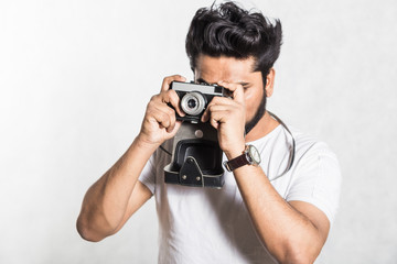 Sticker - Portrait of a handsome young stylish man with beard taking photo on a vintage camera.