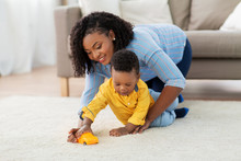 Childhood, Kids And People Concept - Happy African American Mother And Her Baby Son Playing With Toy Car Together On Sofa At Home
