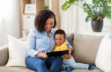 family, motherhood and technology concept - happy african american mother using tablet computer with