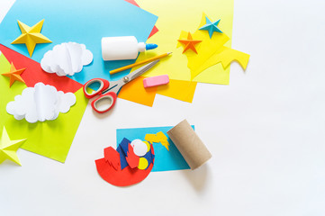 Wall Mural - hands of the child make a paper craft rocket. Cosmos clouds and stars colored paper. The creative process