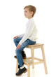 © lotosfoto - A little boy is sitting on a chair.
