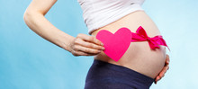 Woman In Pregnant With Pink Ribbon On Belly Holding Heart, Concept Of Expecting For Girl
