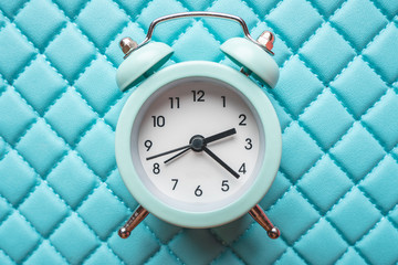 Blue analog metal alarm clock on stylish blue background. Concept of time in pastel colors