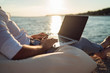 © D'Action Images - Senior man working on his laptop lying on deck chair on the beach during sunset