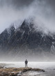 Man stood in front of foggy misty mountain to give scale of mountain size and concept of overpowering challenge