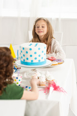 Wall Mural - adorable kids sitting at party table with cake during birthday celebration