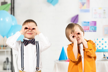 Wall Mural - adorable preteen boys looking at camera through fingers during birthday party