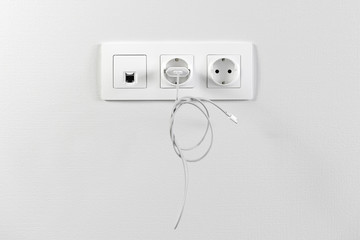 Wall Mural - Electrical sockets on the wall with black connection internet plug and white wire. Adapter from the charging device with usb input plugged in