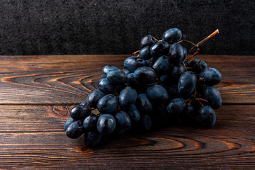 Blue grapes on dark wooden background. 