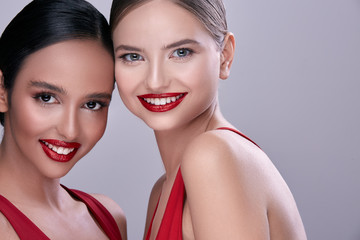 two pretty girls smiling on grey background