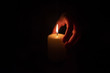© Eduard Vladimirovich - Female hand holding a burning candle in the dark