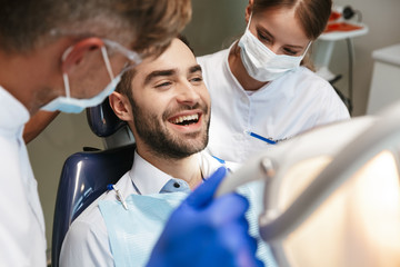 Handsome happy young man sitting in medical dentist center.