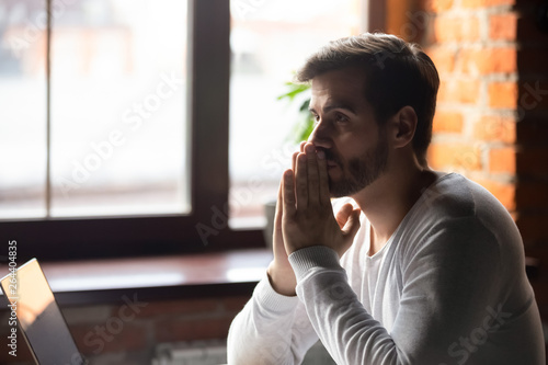 Fotografía Concerned serious doubtful man sitting near laptop and thinking