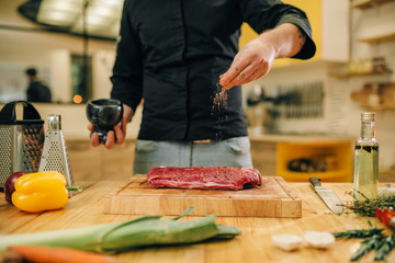 Wall Mural - Male person marinating raw meat on wooden board