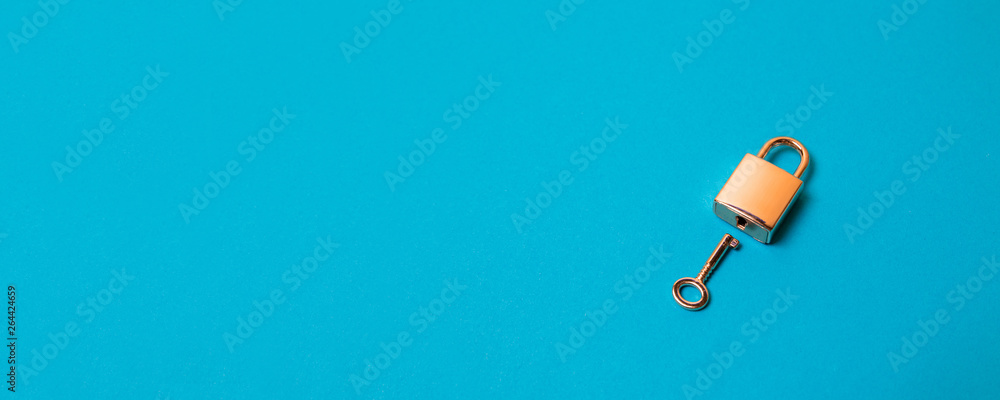 Flat lay protection concept. Locked padlock and key on the blue background. - obrazy, fototapety, plakaty 
