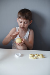 Wall Mural - The child makes cookie molds on a white table. Preparation of homemade dessert