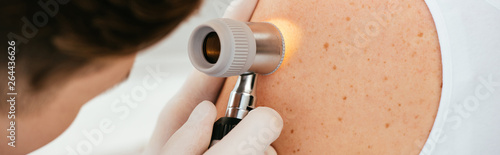 Fotografía panoramic shot of dermatologist in latex gloves holding dermatoscope while exami