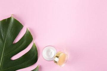 Wall Mural - Moisturizing care skincare face cream for healing complicated troubled skin type in an open jar with visible texture. Copy space, close up, background, flat lay, top view. Monstera leaf decoration.