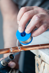 Wall Mural - Closeup professional master plumber holding flux paste for soldering and brazing seams of copper pipe gas burner. Concept installation and repair of an apartment building pipeline, leakage