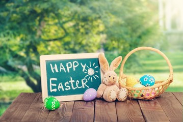 Canvas Print - Painted Easter eggs in a basket on the table with a congratulatory text