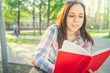 © Anton Dios - Woman with a book in his hands in the Park. Female, student is reading an interesting book sitting on the bench in the park