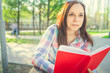 © Anton Dios - Woman with a book in his hands in the Park. Female, student is reading an interesting book sitting on the bench in the park