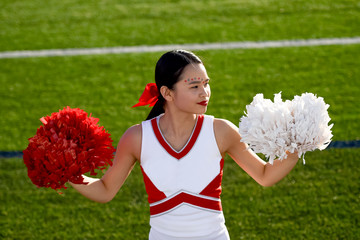 Attractive young cheerleader performing at a high school athletic event