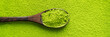 Top view of wooden spoon with green tea Matcha on powder maccha texture background. Long wide banner with copy space.