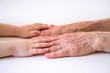 © Ragemax - An elderly woman (old lady, grandmother) holds her little granddaughter's small hands. Family unity, love, help, assistance. Age and generational difference. Aged and wrinkled hands with young hands.