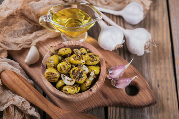 Wall Mural - Grilled olives with garlic, olive oil and spices on rustic wooden table