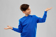 © Syda Productions - childhood, gesture and people concept - smiling boy in blue hoodie holding something imaginary on empty hands over grey background