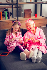 Granny and girl in hair rollers using file nails doing manicure