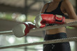 Upset young fighter boxer girl wearing boxing gloves in gymมFemale boxer taking a break from her practice.