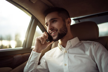 Man talking on smartphone sitting in back seat of car, businessman in taxi