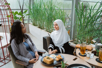 Canvas Print - muslim woman talking in cafe together. girl with scarf having a chat