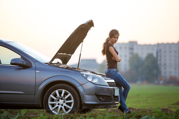 Young woman and a car with popped hood. Transportation, vehicles problems and breakdowns concept.