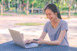 © TeTe Song - Young girl is a university student with cup of coffee and a phone in her hands working on a laptop at the table in the park. The concept of shopping online in the Internet