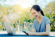 © TeTe Song - Successful young girl is a university student with cup of coffee and a phone in her hands working on a laptop at the table in the park. The concept of shopping online in the Internet