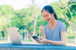 © TeTe Song - Successful young girl is a university student with cup of coffee and a phone in her hands working on a laptop at the table in the park. The concept of shopping online in the Internet