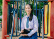 © TeTe Song - Lovely teenage girl wearing school uniform writing book while sitting on a swing at the park.