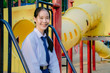 © TeTe Song - Portrait of asian girl student in school uniform Thailand style, sitting on swing and enjoy herself in windy and sunny day.