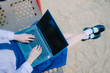 © TeTe Song - Top view of lovely teenage girl wearing school uniform sitting on swing in the park on the sand with laptop, notebook, hands on keyboard.