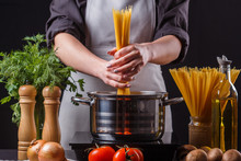 Young Woman In A Gray Apron Preparing Pasta
