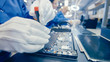 © Gorodenkoff - Close-Up of a Female Electronics Factory Worker in Blue Work Coat Assembling Laptop's Motherboard with a Screwdriver. High Tech Factory Facility with Multiple Employees.