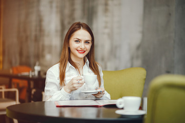 Beautiful girl with coffee. The woman is sitting at the table. Elegant lady in the cafe