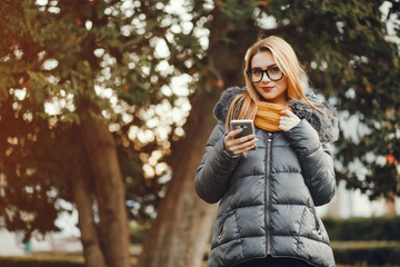 Beautiful girl in the park. Girl in glasses. Woman with phone