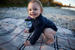 © Westend61 - Portrait of smiling toddler girl crouching barefoot on blanket on the beach