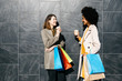 © Westend61 - Two happy women with shopping bags and takeaway coffee standing at a wall talking